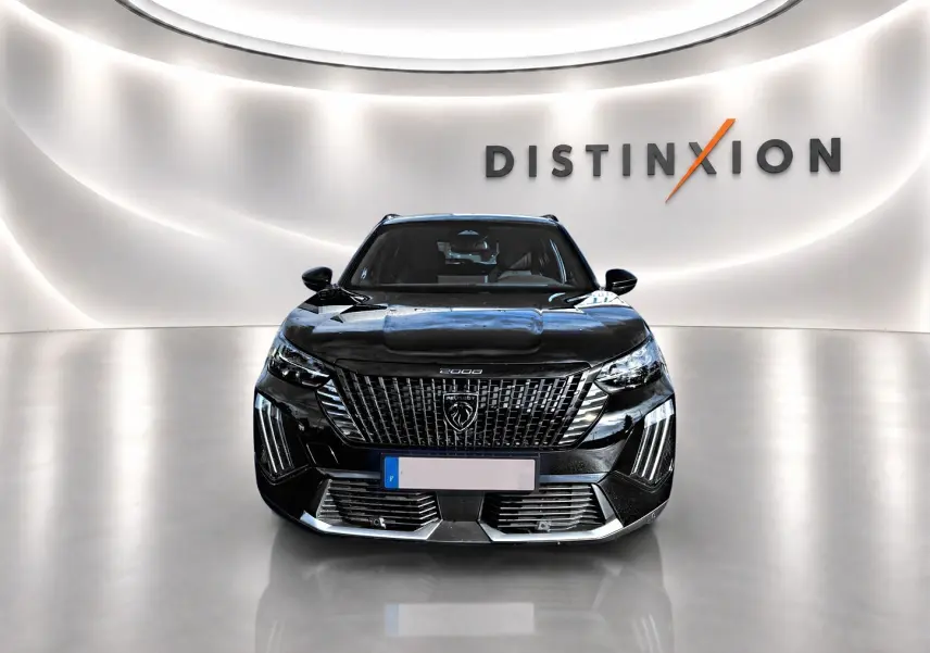 Vue frontale d’un Peugeot 2008 noir brillant avec calandre imposante et logo lion au centre, dans un showroom lumineux.
