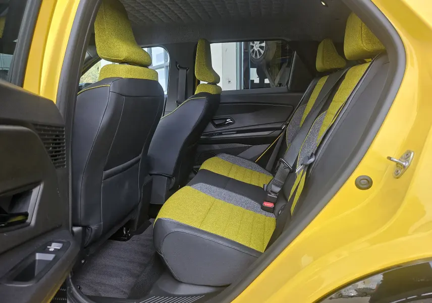 Vue latérale arrière montrant l'intérieur arrière jaune et gris du Renault R5 Iconic 2025 avec porte ouverte côté droit.