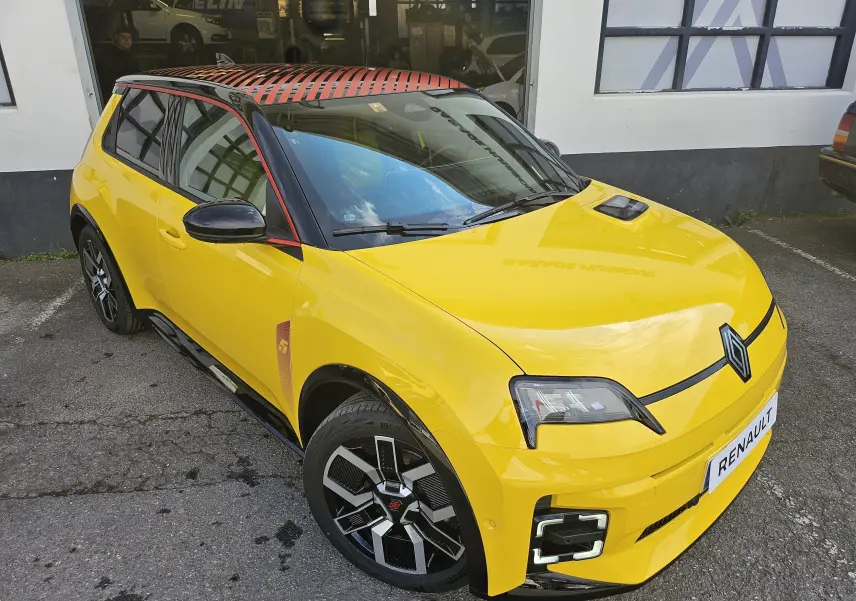 Renault R5 Iconic jaune pop avec toit noir, vue 3/4 avant droit mettant en valeur ses phares LED et jantes stylisées.