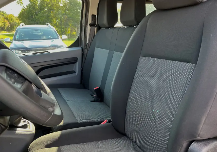 Vue intérieure côté conducteur du Citroën Jumpy Spacetourer 2022, sièges tissu noir et gris, volant partiellement visible.