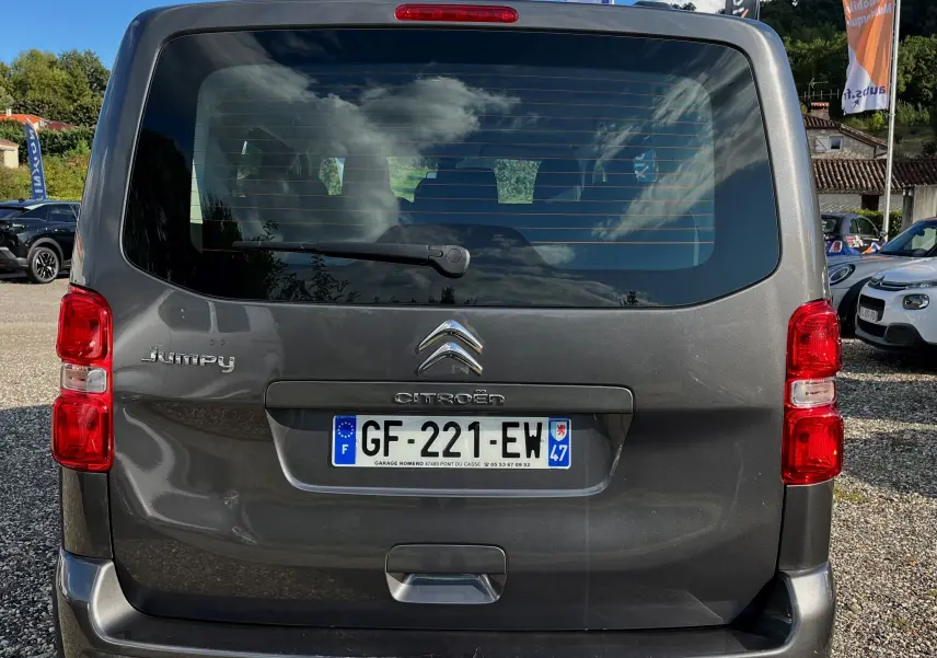 Vue arrière d'un Citroën Jumpy gris métallisé avec plaque française, feux rouges et lunette arrière teintée.