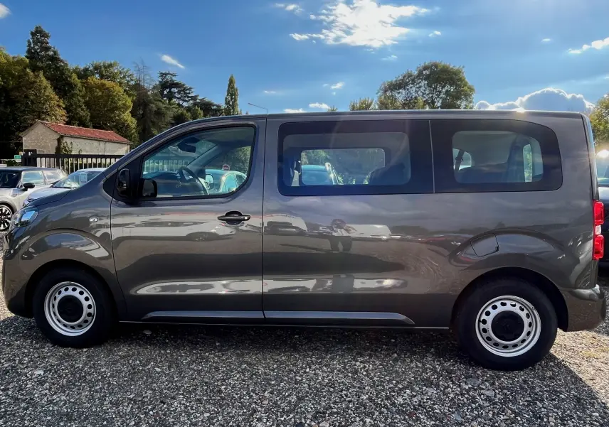 Profil côté gauche d'un Citroën Spacetourer gris 2022 avec 9 places, roues acier et vitres latérales teintées.