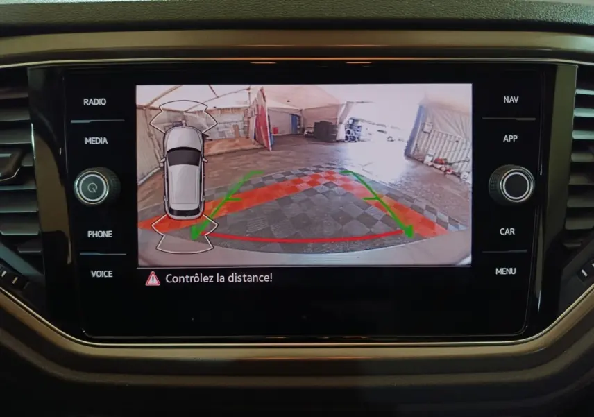 Écran tactile intérieur affichant la caméra de recul et l'aide au stationnement du Volkswagen T-Roc gris foncé.