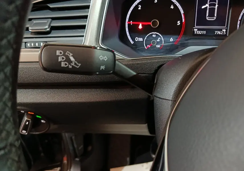 Gros plan sur la manette de clignotants et le tableau de bord numérique du Volkswagen T-Roc gris foncé, vue côté conducteur.