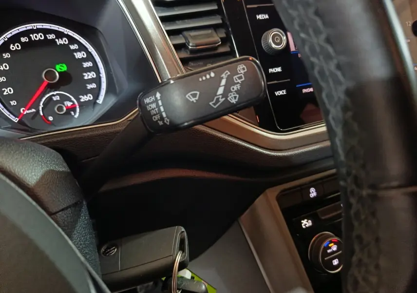 Gros plan intérieur sur le volant et le commodo d’essuie-glace du Volkswagen T-Roc 2.0 TDI 150 gris foncé, tableau de bord visible.