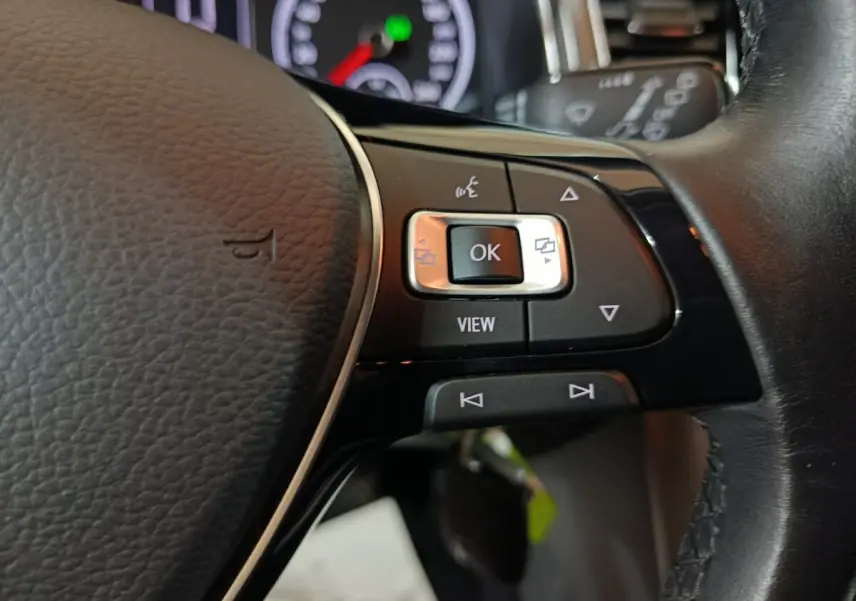 Gros plan sur les commandes multifonctions à droite du volant cuir du Volkswagen T-Roc gris foncé, tableau de bord en arrière-plan.