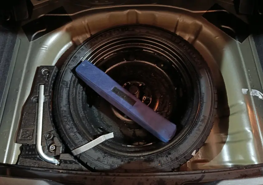 Vue rapprochée de la roue de secours et des outils dans le coffre d'un Volkswagen T-Roc gris foncé 2021.