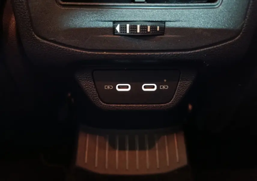 Gros plan sur les deux ports USB-C lumineux situés à l'arrière de la console centrale du Volkswagen T-Roc gris foncé.