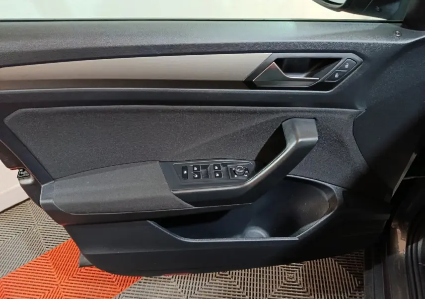 Vue intérieure du panneau de porte avant gauche du Volkswagen T-Roc gris foncé, avec commandes des vitres et verrouillage.
