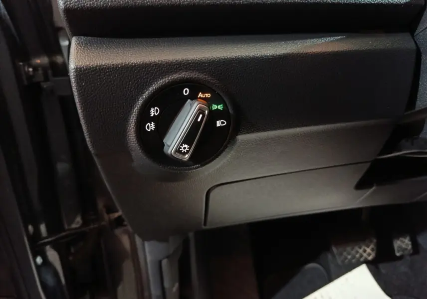 Gros plan sur le bouton de commande des phares du Volkswagen T-Roc gris foncé, côté conducteur, intérieur avant.