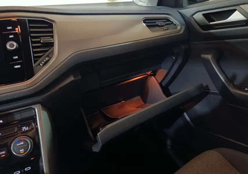 Intérieur du Volkswagen T-Roc 2021 gris foncé, vue côté passager avec boîte à gants ouverte et tableau de bord tactile.