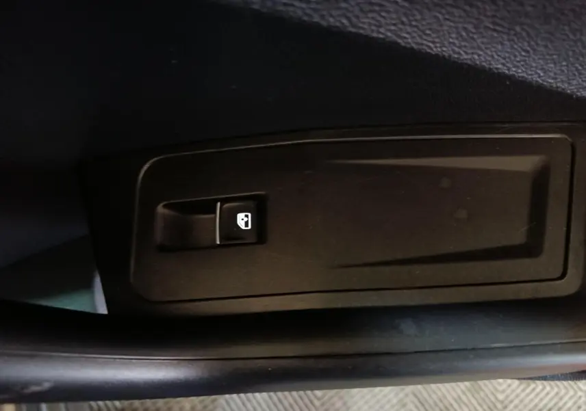 Bouton de commande de lève-vitre électrique sur la porte intérieure côté conducteur du Volkswagen T-Roc gris foncé.