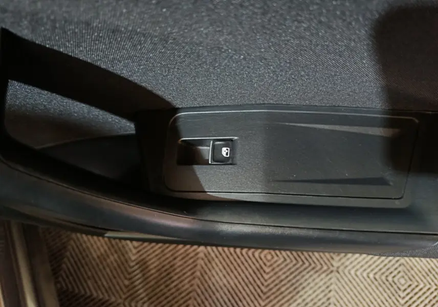 Gros plan sur le levier d'ouverture de trappe à carburant dans l'habitacle du Volkswagen T-Roc gris foncé.