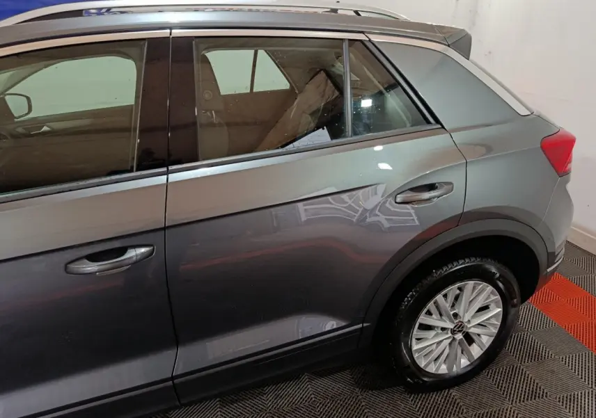 Vue latérale droite du Volkswagen T-Roc gris foncé, mettant en valeur les jantes alliage et les contours de fenêtres chromés.
