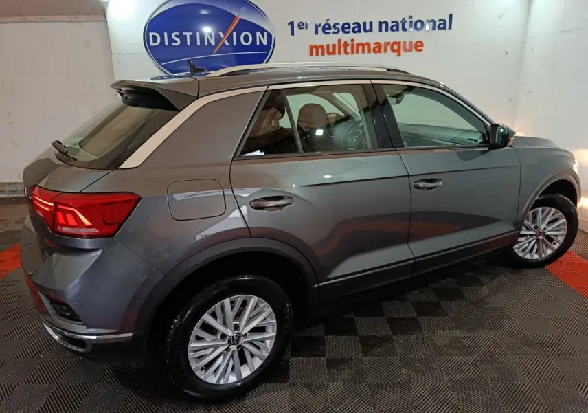 Vue 3/4 arrière droite d’un Volkswagen T-Roc gris foncé 2021 avec jantes alliage et feux arrière LED allumés.