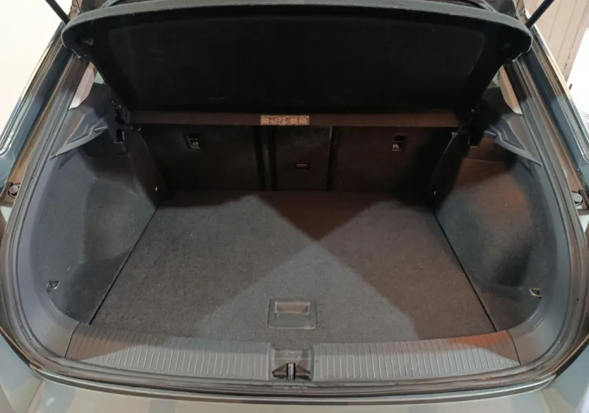 Coffre ouvert vu de l'arrière d'un Volkswagen T-Roc gris foncé, espace de chargement propre et vide.