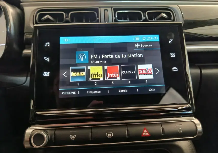 Écran tactile central de 7 pouces du tableau de bord de la Citroën C3 blanche, affichant les stations radio FM.