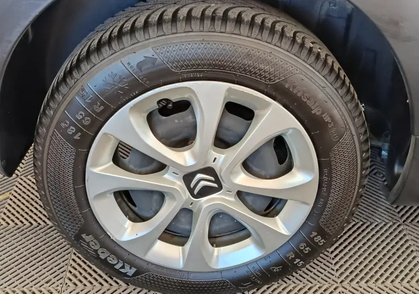 Gros plan sur la roue arrière droite d'une Citroën C3 blanche, montrant le pneu et l'aile du véhicule.