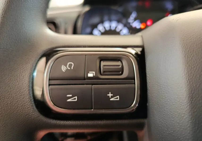 Gros plan sur les commandes au volant à gauche du tableau de bord d’une Citroën C3 blanche, version 2020.