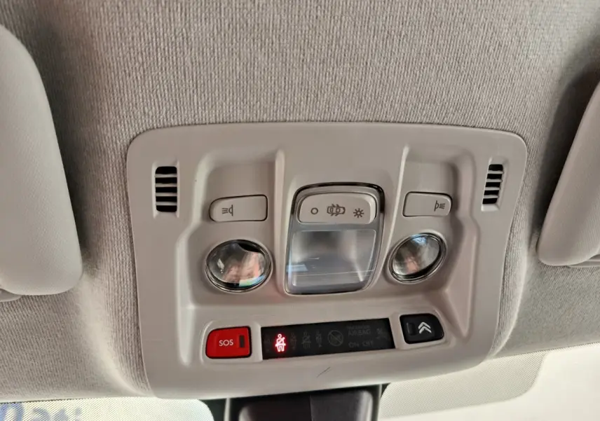 Plafonnier intérieur avec commandes d’éclairage et bouton SOS dans une Citroën C3 blanche, vue du plafond vers l’avant.