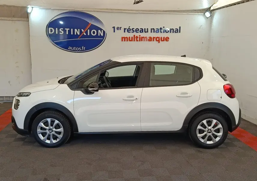 Profil côté gauche d'une Citroën C3 blanche 2020 avec jantes alliage et rétroviseurs noirs dans un showroom.