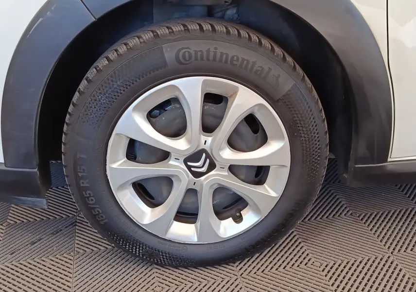 Gros plan sur la roue avant gauche d'une Citroën C3 blanche, avec jante argentée et logo Citroën central.