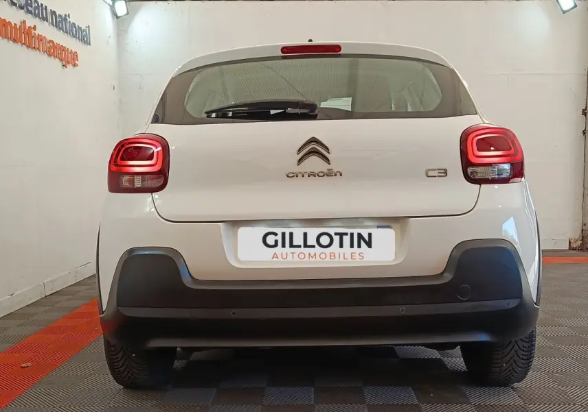 Vue arrière d'une Citroën C3 blanche avec feux arrière LED et pare-chocs noir mat dans un garage.