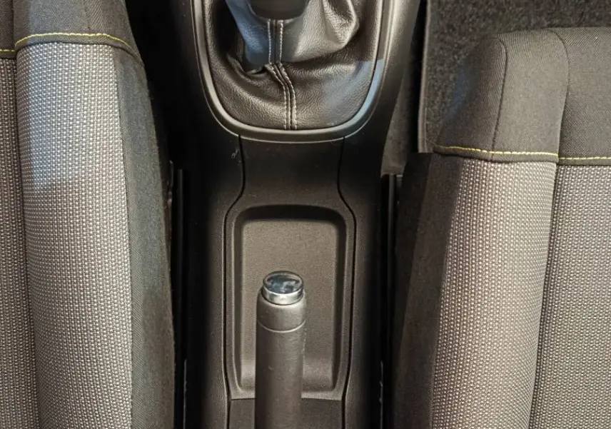 Vue plongeante sur la console centrale de la Citroën C3 2020, montrant levier de vitesse manuel et frein à main entre sièges gris.
