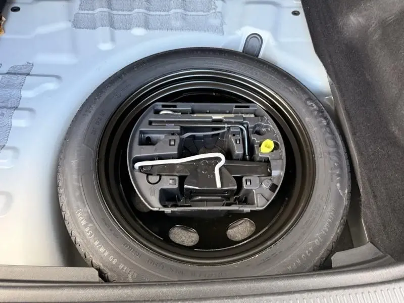 Vue rapprochée du coffre du DS7 Crossback blanc 2019, montrant la roue de secours avec son kit d'outils intégré.