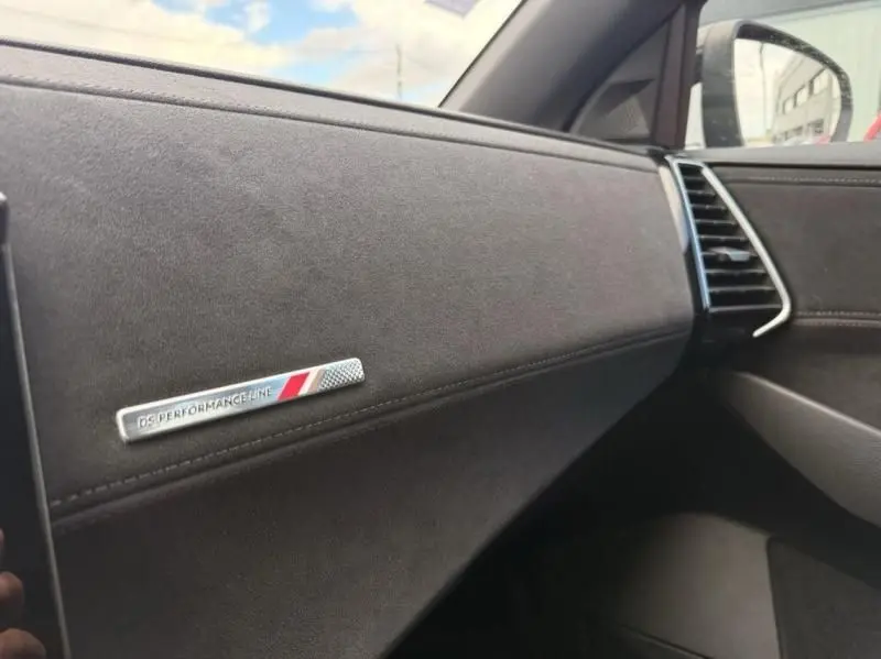 Détail intérieur côté passager du DS7 Crossback blanc 2019, mettant en valeur l’inscription DS Performance Line sur la planche de bord.
