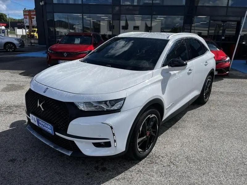 DS7 Crossback blanc vue 3/4 avant droit, calandre noire distinctive et jantes noires, stationné en extérieur.