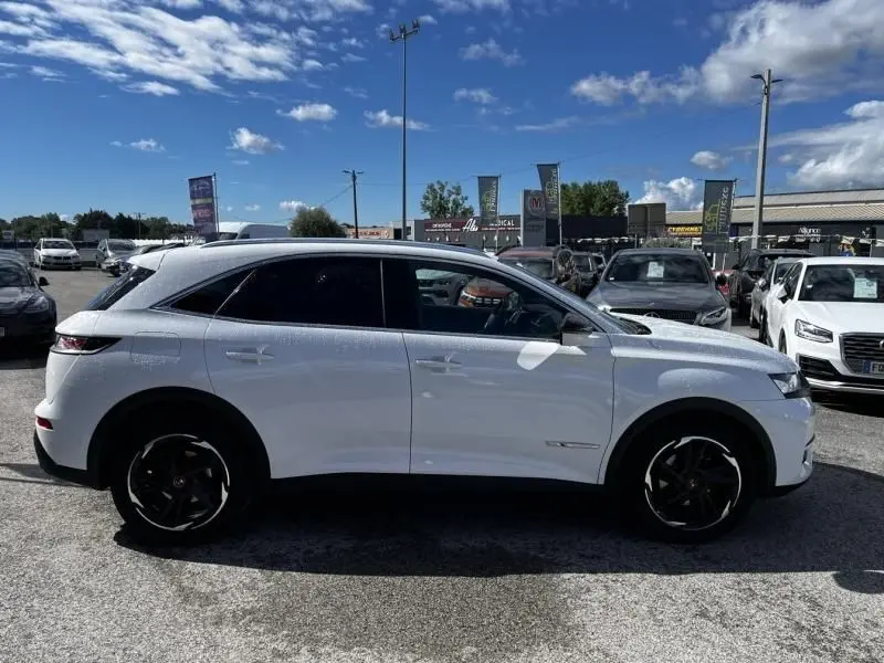 Vue de profil côté gauche d’un DS7 Crossback blanc 2019 HDI 130 Performance Line avec jantes noires et vitres teintées.