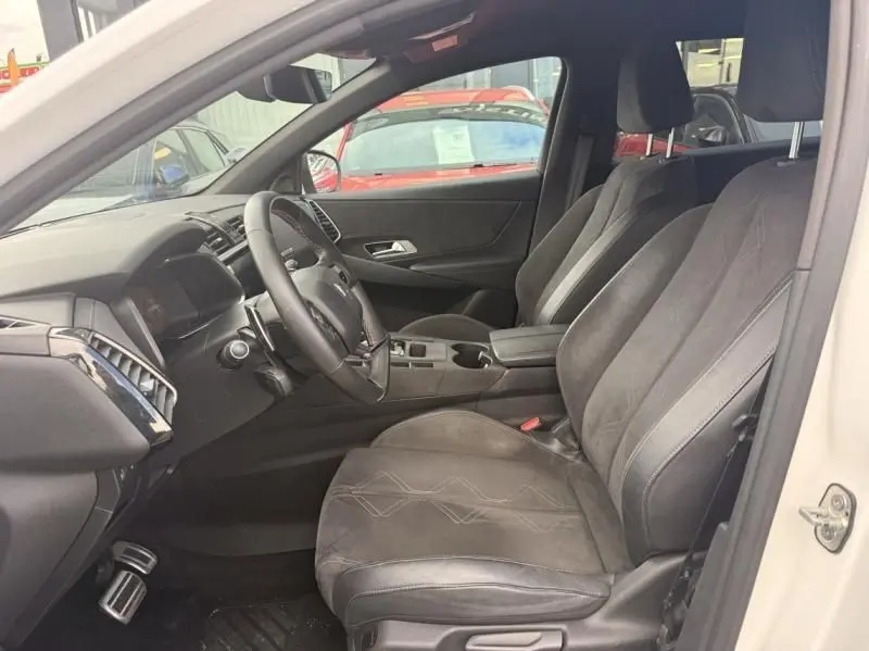 Vue intérieure côté conducteur du DS7 Crossback blanc 2019, sièges en cuir noir et tableau de bord moderne.