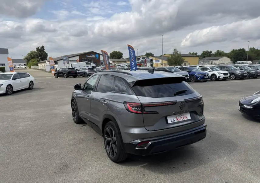 Renault Austral gris 3/4 arrière droit, vitres surteintées et jantes aluminium noires sur parking.