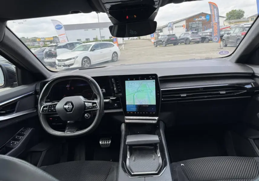 Vue intérieure avant du Renault Austral gris 2023, mettant en valeur le volant multifonctions et l'écran tactile central avec GPS.