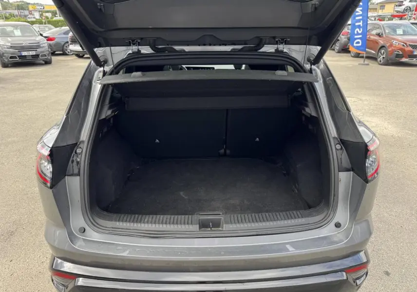 Coffre ouvert vu de l'arrière d'un Renault Austral gris 2023, avec cache-bagages et hayon relevé.