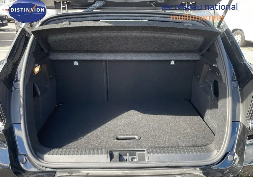 Coffre ouvert vu de l'arrière d'un Renault Captur noir étoile métal avec toit gris, montrant un espace de chargement propre et spacieux.
