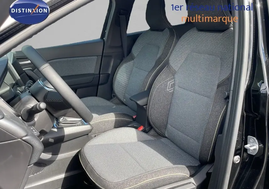 Vue intérieure côté conducteur du Renault Captur 2025, sièges tissu gris avec surpiqûres contrastées, portière noire ouverte.