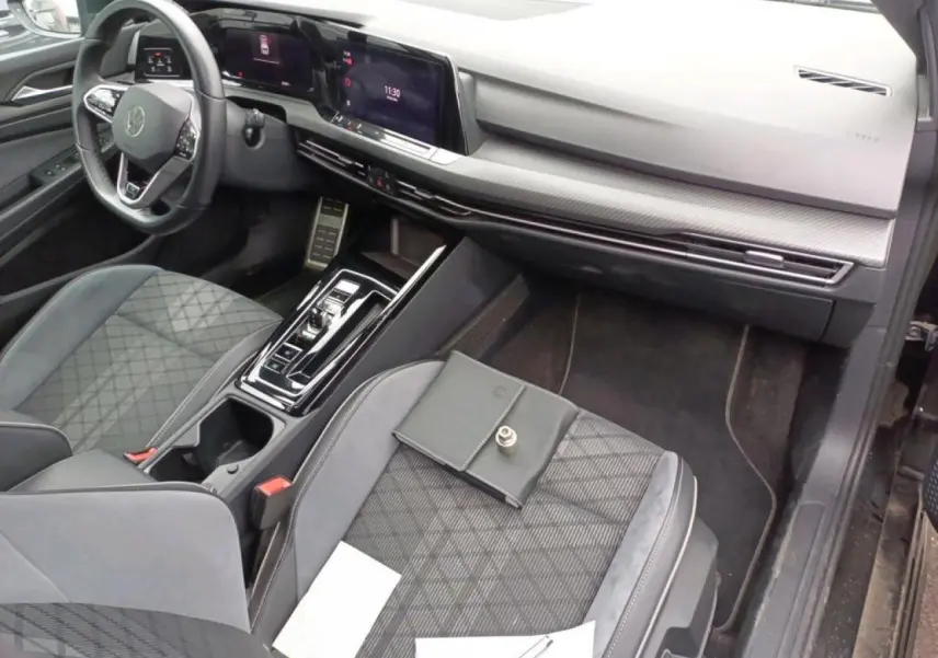 Vue intérieure côté passager avant de la Volkswagen Golf 8 R-Line 2024 avec sellerie tissu noire et console centrale moderne.