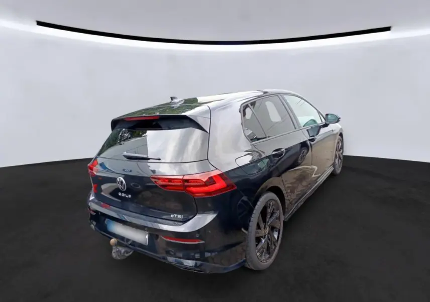 Volkswagen Golf 8 noir vue 3/4 arrière droit avec attelage escamotable et jantes noires 18 pouces.