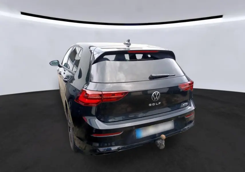 Volkswagen Golf 8 noir vue 3/4 arrière avec attelage escamotable et feux arrière LED défilants.