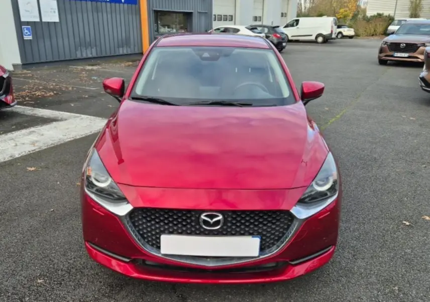 Vue frontale d'une Mazda2 rouge vif 2021 avec calandre noire et phares LED distinctifs.