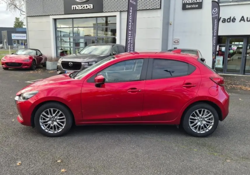 Vue latérale droite d'une Mazda2 rouge 2021 avec jantes aluminium, vitres surteintées et rétroviseurs assortis.