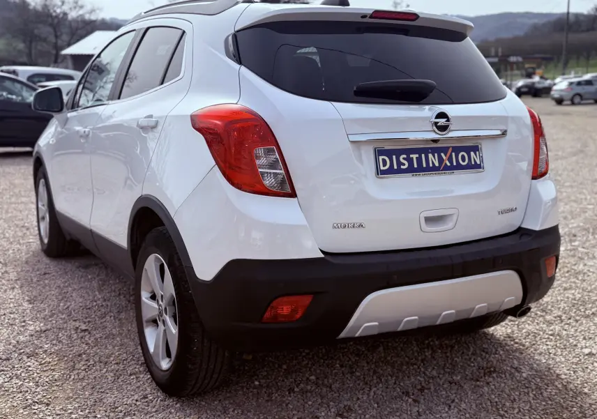 Vue 3/4 arrière droite d'un Opel Mokka X blanc avec feux arrière rouges et plaque d'immatriculation Distinxion.