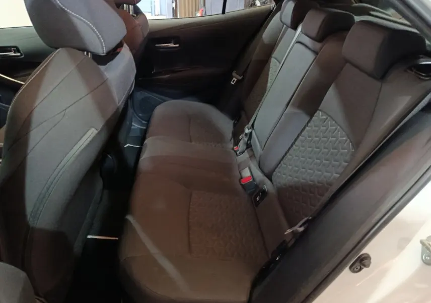 Vue intérieure côté droit sur la banquette arrière noire de la Toyota Corolla Hybride 2022, porte ouverte blanche visible.