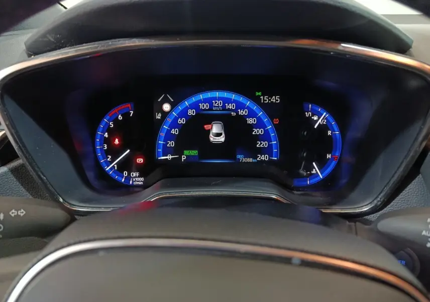 Vue rapprochée du combiné d'instruments numérique bleu de la Toyota Corolla hybride 2022, affichant 73 088 km.