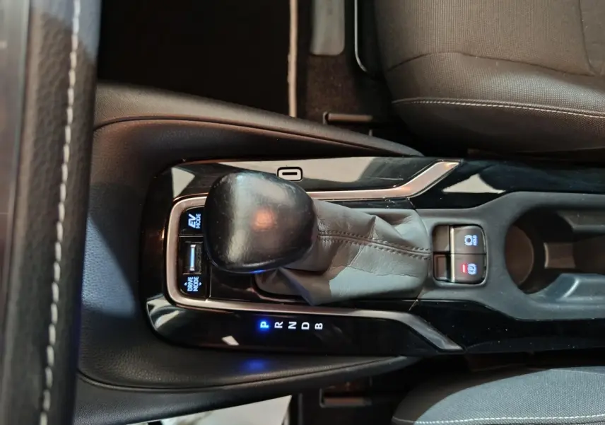 Gros plan sur la console centrale de la Toyota Corolla hybride blanche, montrant le levier de vitesse et les boutons lumineux.