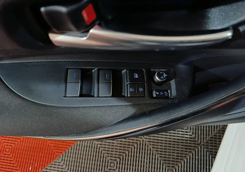 Gros plan sur les commandes des vitres et rétroviseurs côté conducteur de la Toyota Corolla hybride blanche 2022.