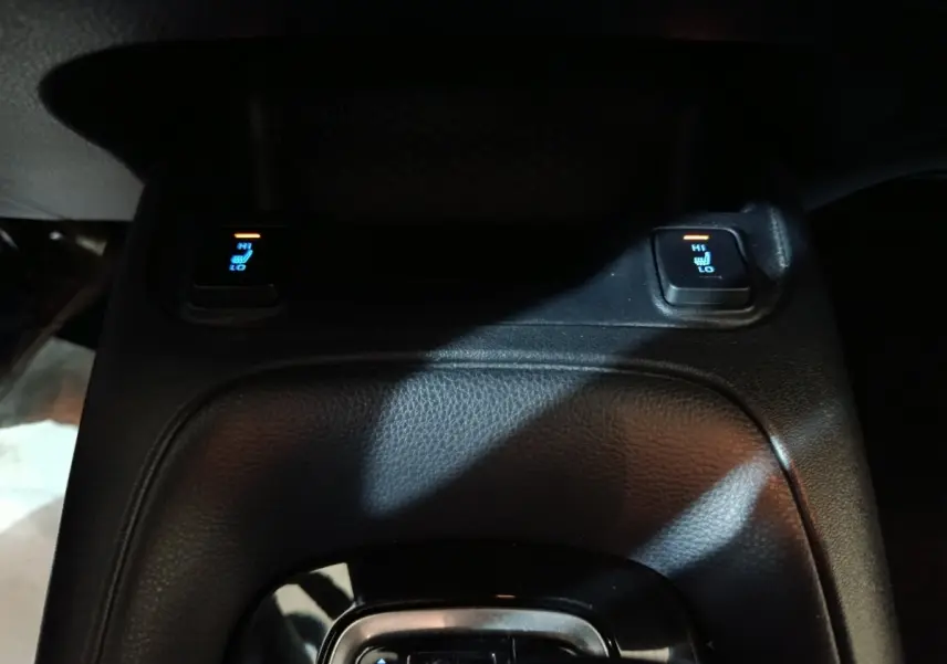 Gros plan sur la console centrale noire avec commandes de sièges chauffants de la Toyota Corolla hybride blanche 2022.