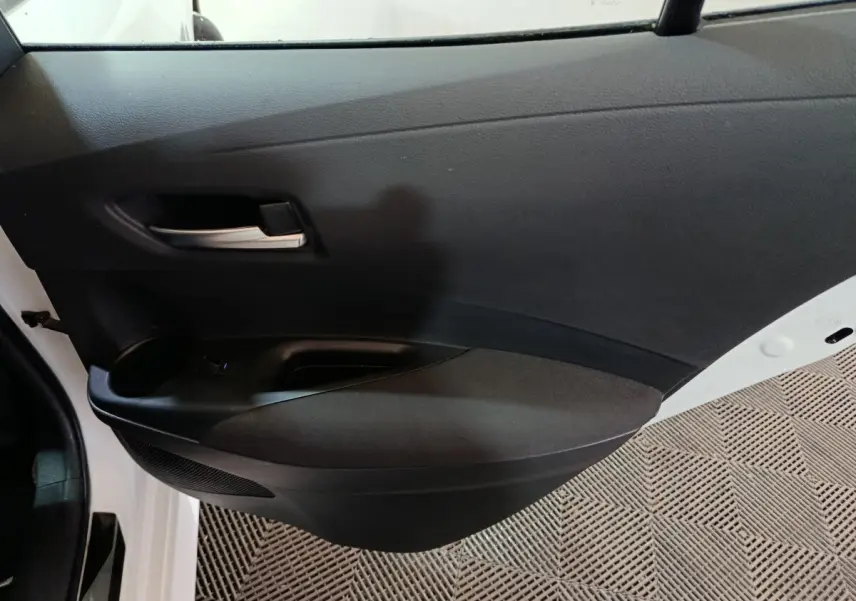 Vue intérieure côté gauche de la porte avant noire d'une Toyota Corolla hybride blanche 2022 avec poignée argentée.